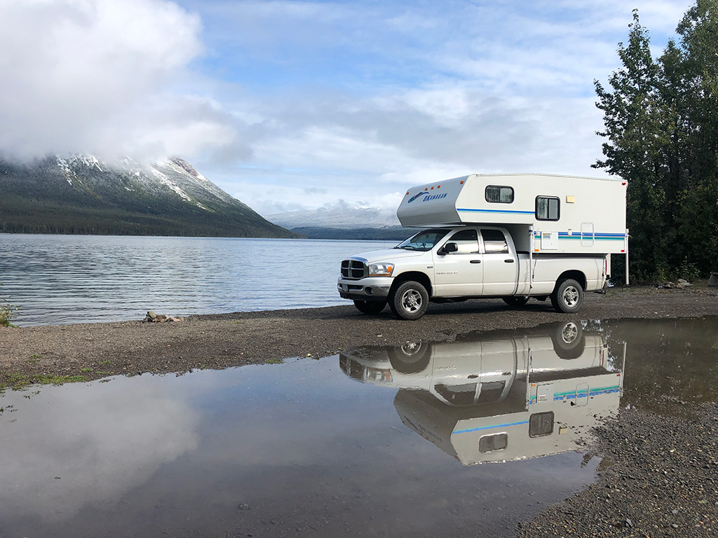 camper truck with reflection in the water - how to choose vehicle for roadtrip