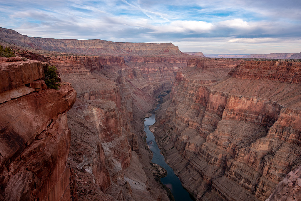 Toroweap Overlook with Colorado River at the bottom of deep canyon walls in orange and red colors.