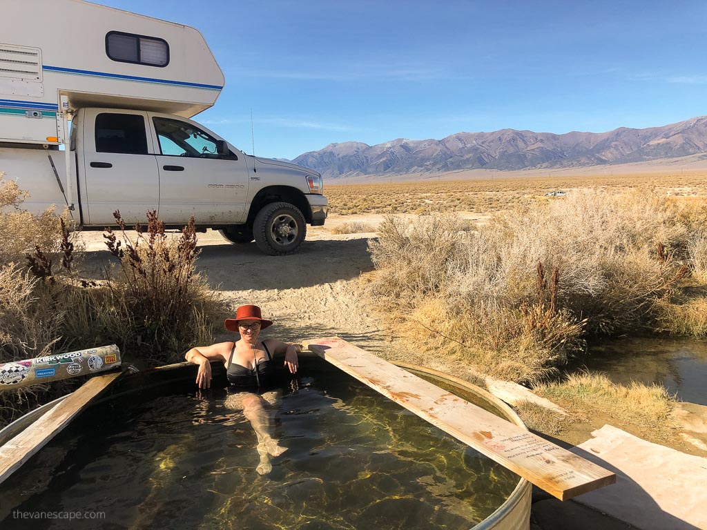 Agnes Stabinska, the author, is relax in spencer hot springs in nevada. At the backdrop is our camper truck and mountains.