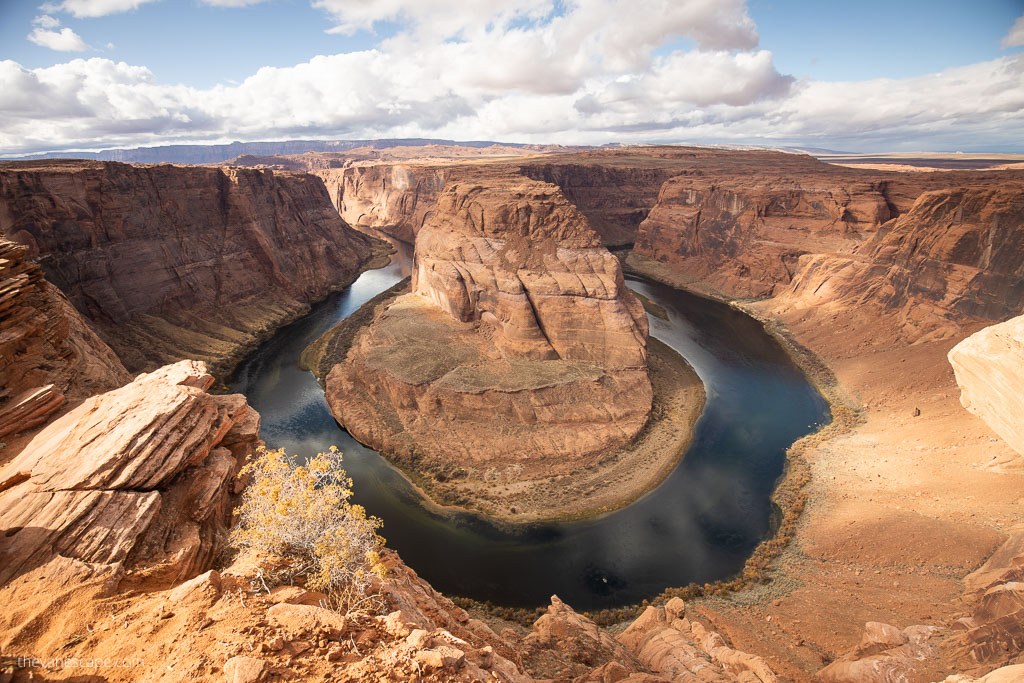 Horseshoe bend hike guide: clouds over the orange walls and above blue water.