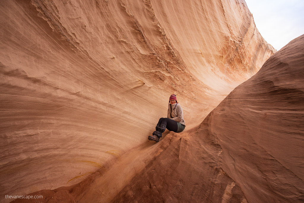 Agnes Stabinska, the author, sits on the orange rocks formations carved by water known as The Nautilus Hike.