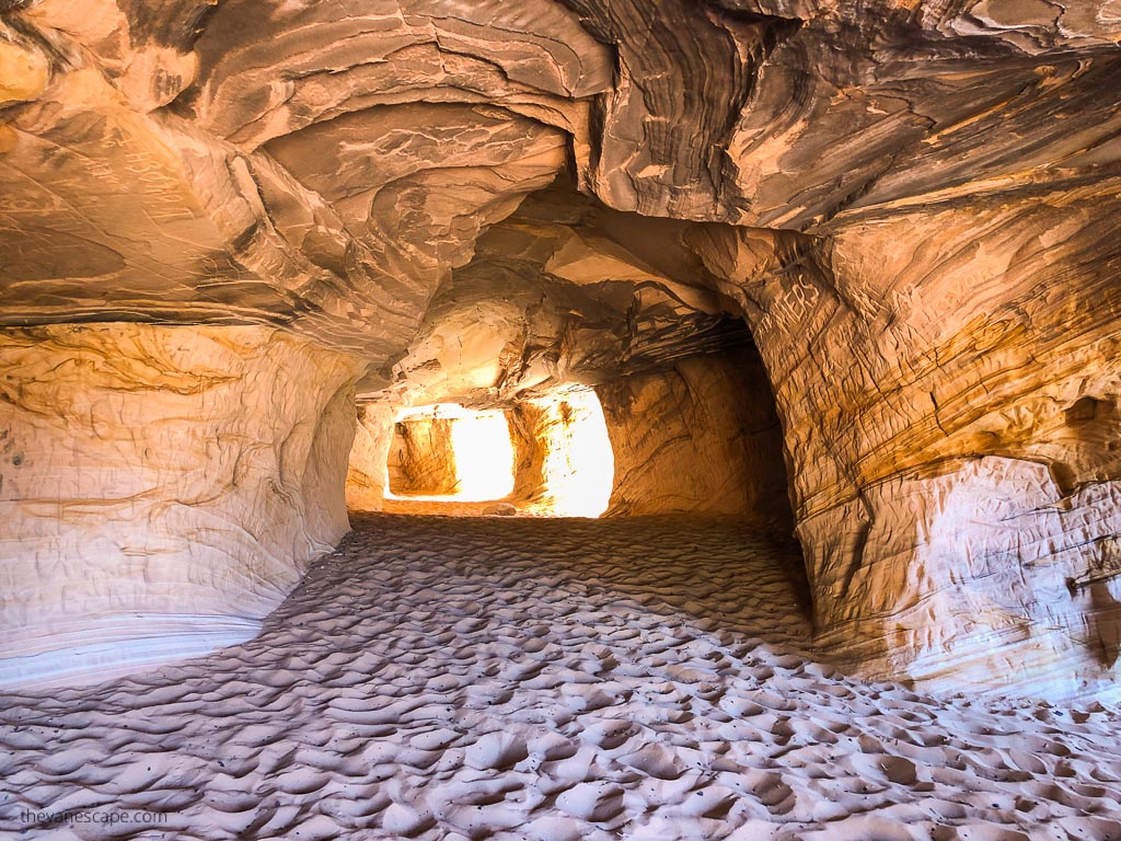 Scratched yellow and orange walls inside the Moqui Caverns near Kanab and yellow sand at the bottom of the cave.