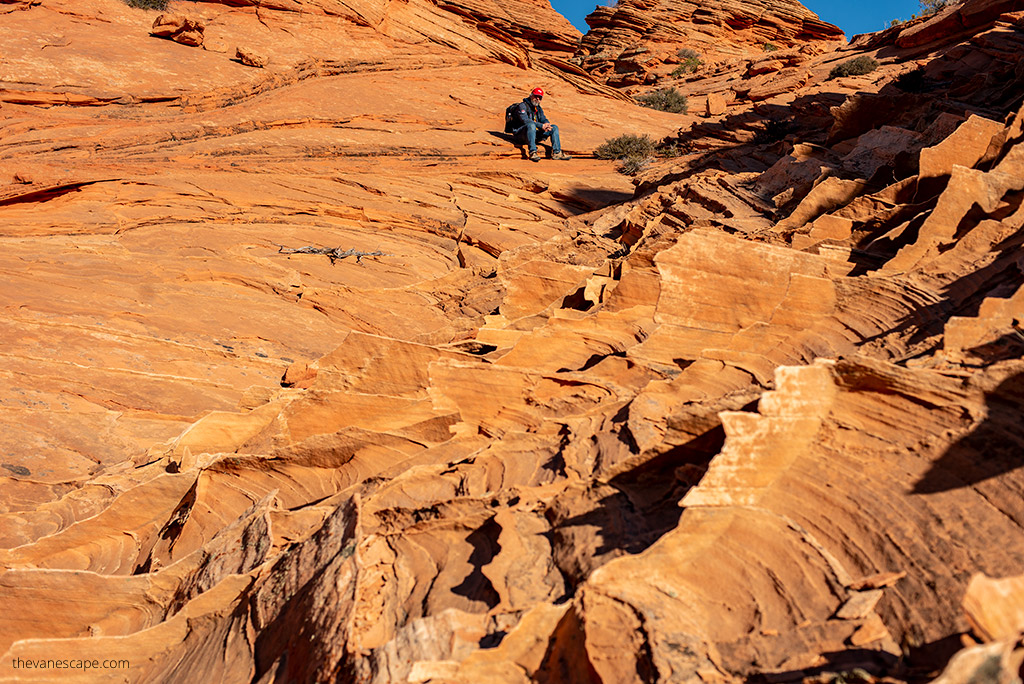 Chris Labanowski, the co-founder of the Van Escape blog is sitting on the orange rock forations of Coyote Buttes.