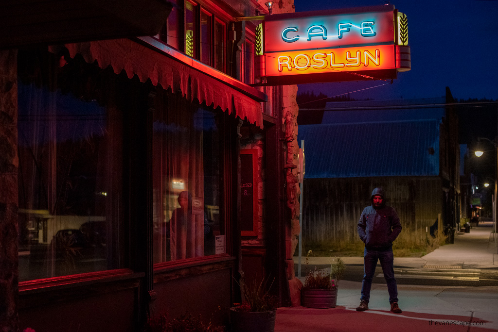 Chris, co-founder of the Van Escape blog, is standing next to Roslyn Cafe neon, it's night.