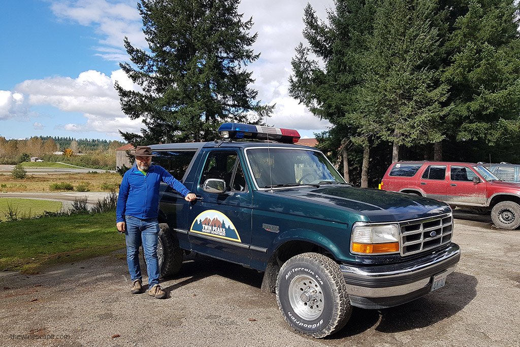 Chris Labanowski, co-founder of the Van Escape blod is standing next to the Twin Peaks sheriff car.