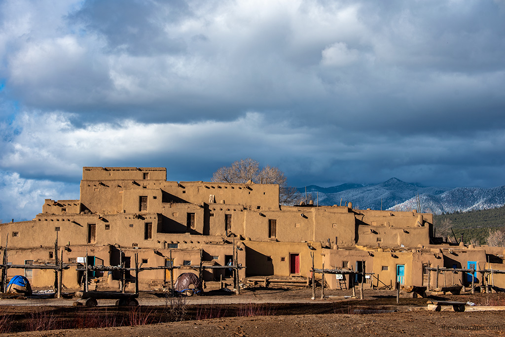 Taos Pueblo historical buildlings witjh mountain view in the backdrop.