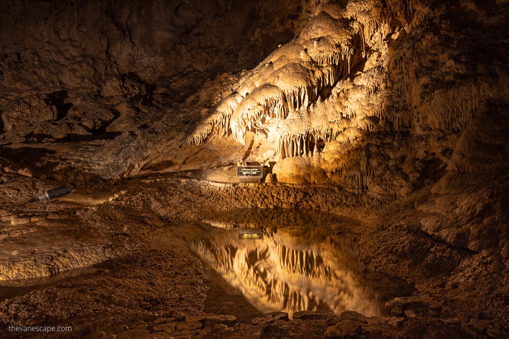 Stunning stalactites and stalagmites in the softly lit cave are reflecting in the water in the cave in Carlsbad cavern. 