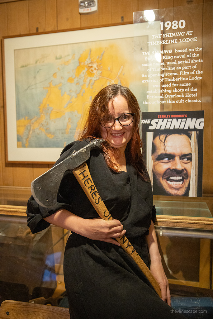 Agnes Stabinska, the author, with the ax used by Jack Nicolson during the filming of The Shining in the Timberline Lodge. In the background there is a poster from the film with the actor.