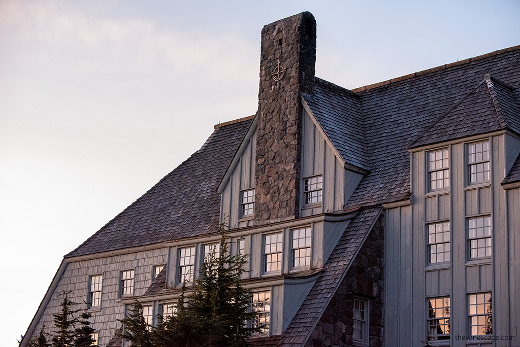 the large windows and stone chimney of the historic Timberline Lodge during sunset