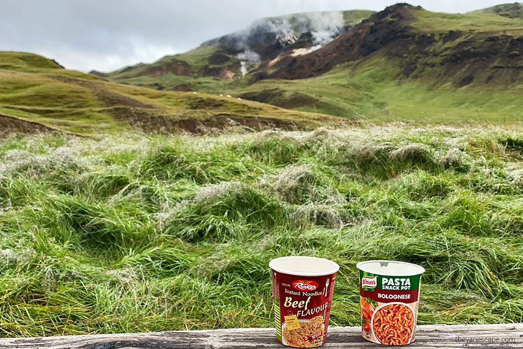 Camping food: two packages of instant noodles against the background of mountains.