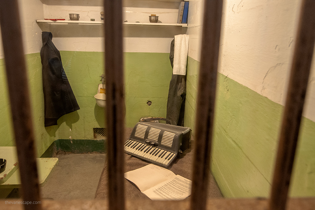 cell in prison with a desk and musical instrument: organ and sheet music on it.