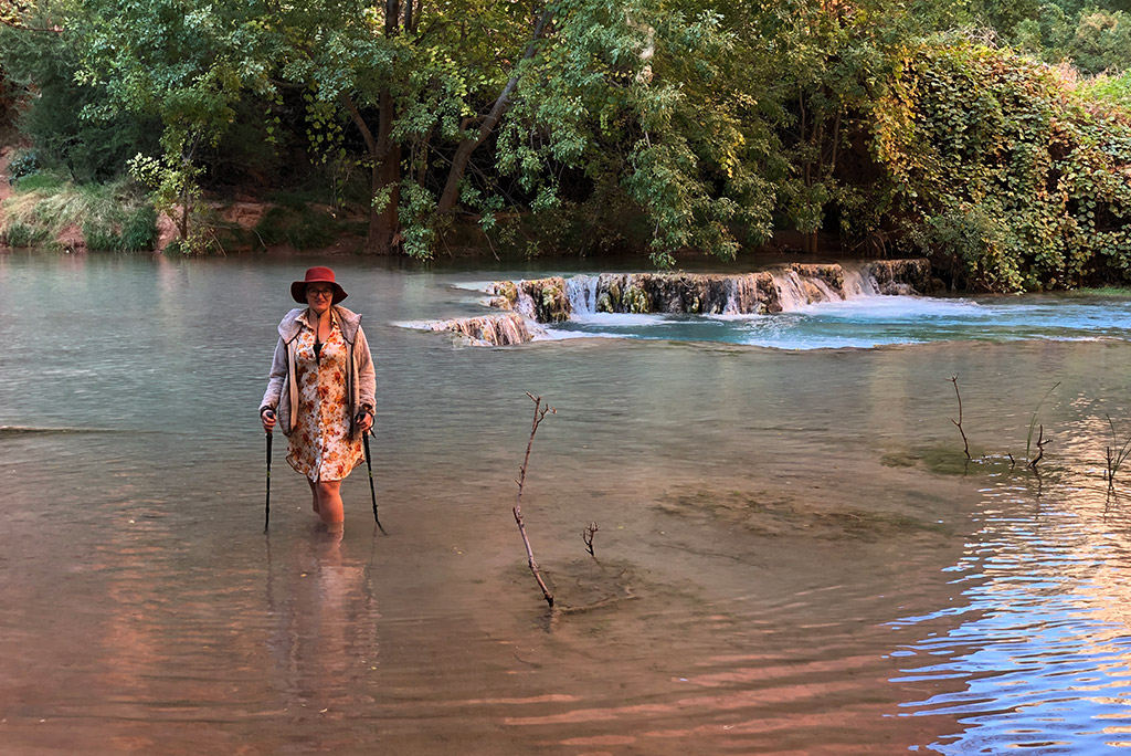 Agnes Stabinska, the author, is crossing the river with the help of trekking poles.