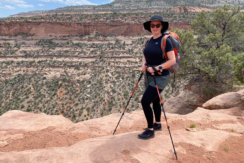 Agnes Stabinska, the author and co-owner of the Van Escape blog, is standing on a hiking trail with Black diamond trekking poles in her hands.