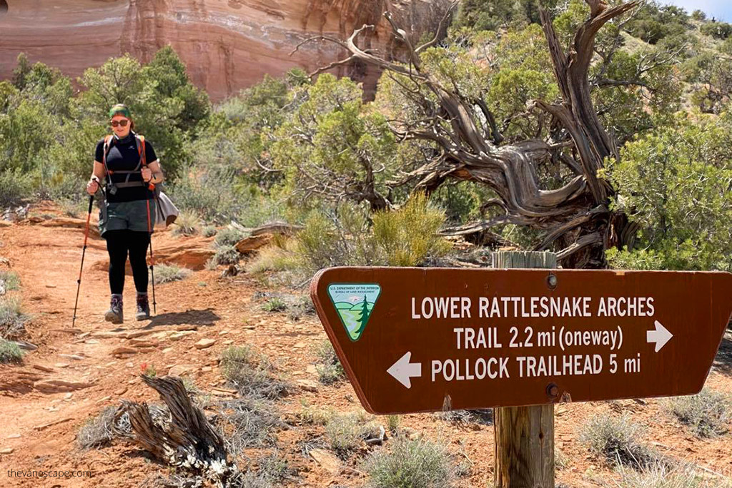 Agnes Stabinska, the author, with trakking poles on the trailhead. At the front is a BLM sign with trail directions.