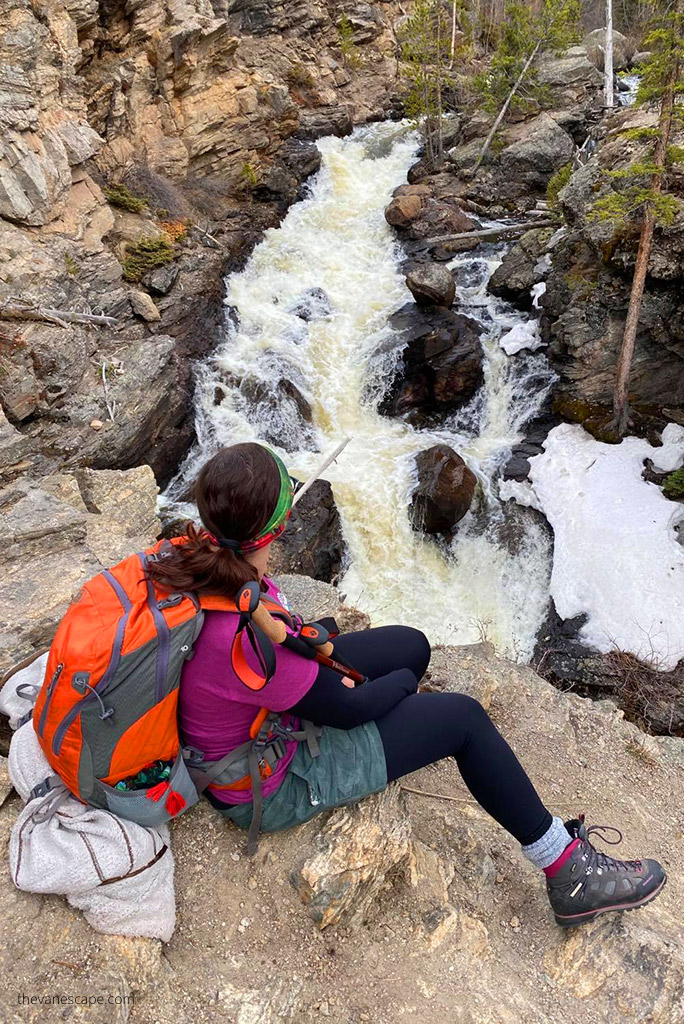 Agnes Stabinska, the author and co-owner of the Van Escape blog, is sitting on the rock and admiring Adams Falls in Rocky Mountains.