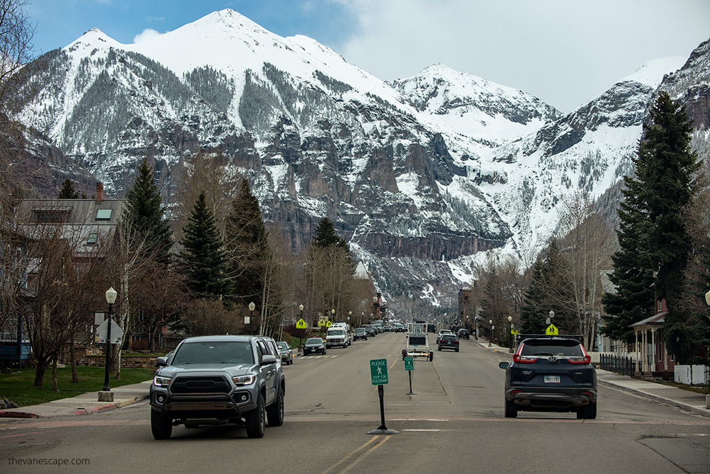 cars on the road on The San Juan Skyway with mountain peaks covered by snow in the backdrop.