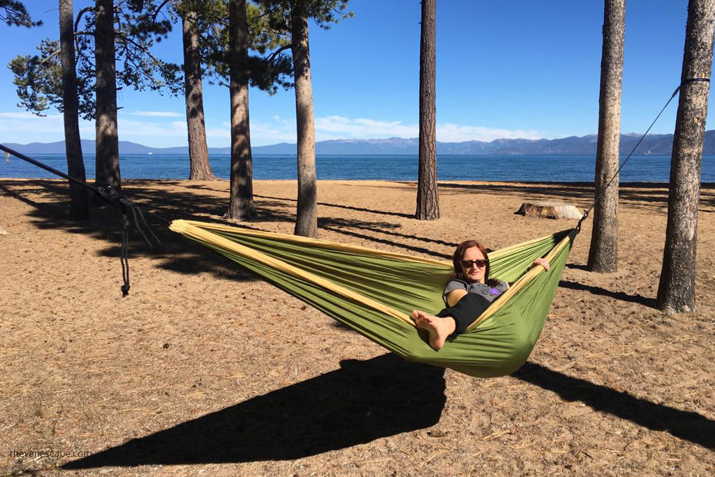 Agnes Stabinska, the author and co-founder of the Van Escape blog, is hanging in a green hammock with the lake and mountain view.