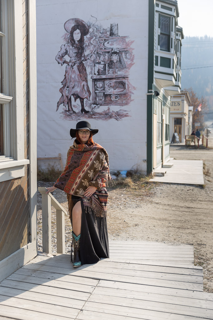 Agnes Stabinska, the author in long black dress, black hat and cowboy boots on the wooden broadwalk in Dawson City.