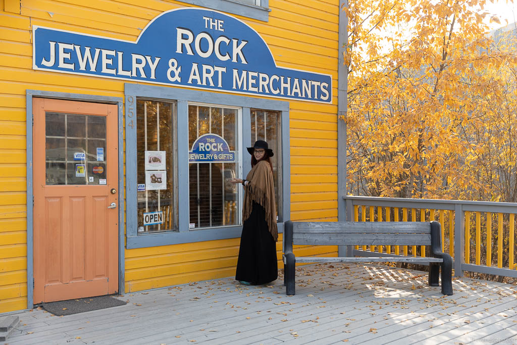 Agnes Stabinska at the entrance to yellow wooden store with inscription: the rock jewelry and art merchants