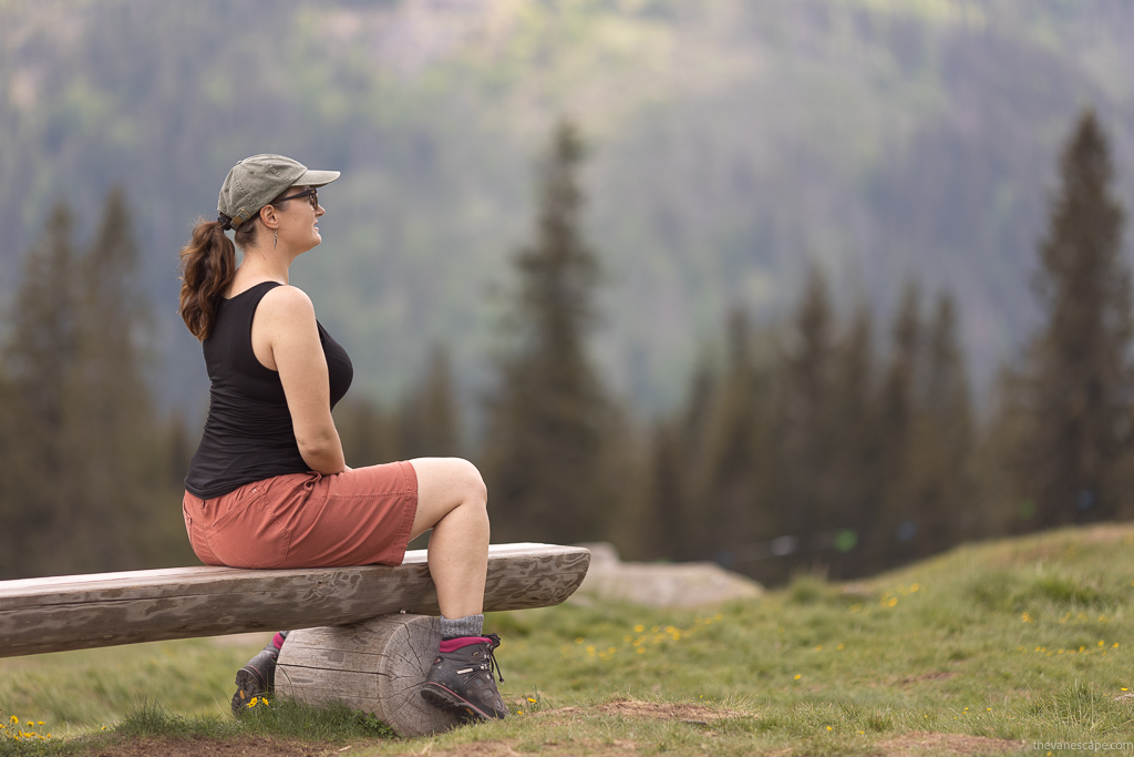 Agnes Stabinska, the author and co-owner of the Van Escape blog is sitting on a wooden bench in KUHL KULTIVATR Women's Shorts, hiking boots and black t-shirt.