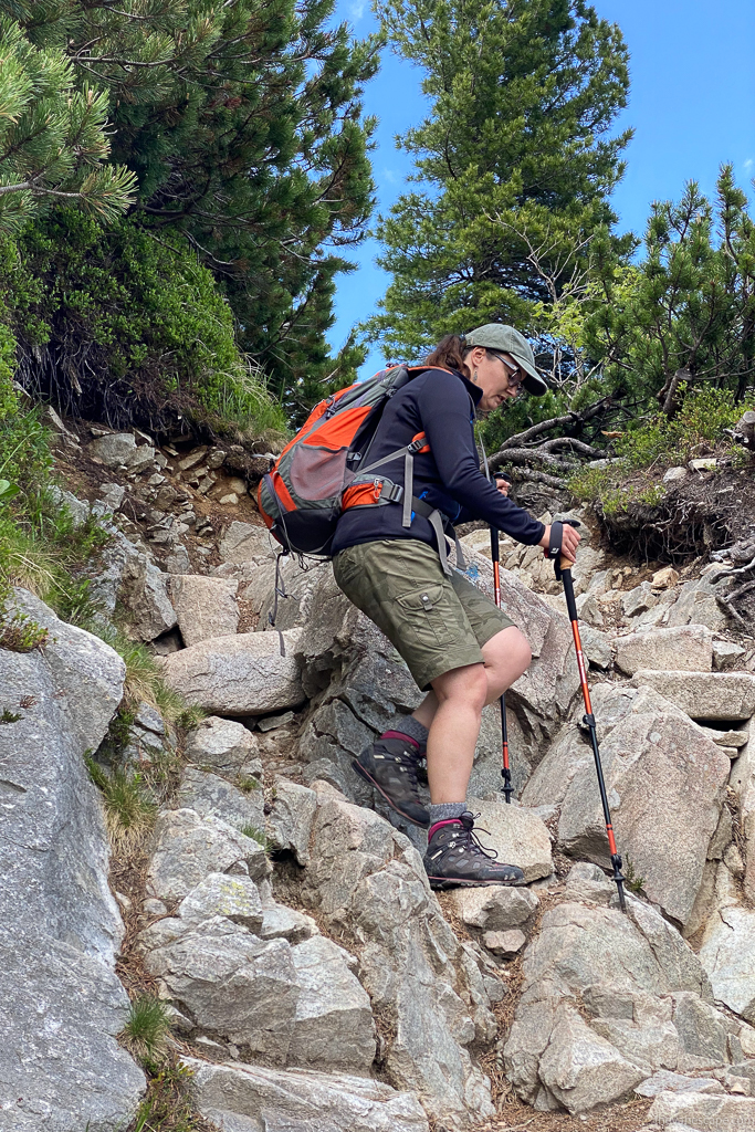 Agnes in KUHL SPLASH 11" shorts and hiking boots and with trekking poles on the hiking trail.