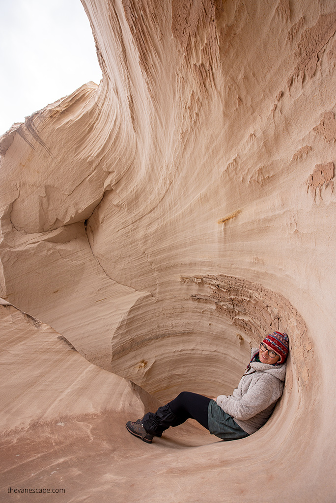 Agnes Stabinska in KUHL Fleece Flight Jacket sits next to delicate rock wall in light color on the hiking trail.