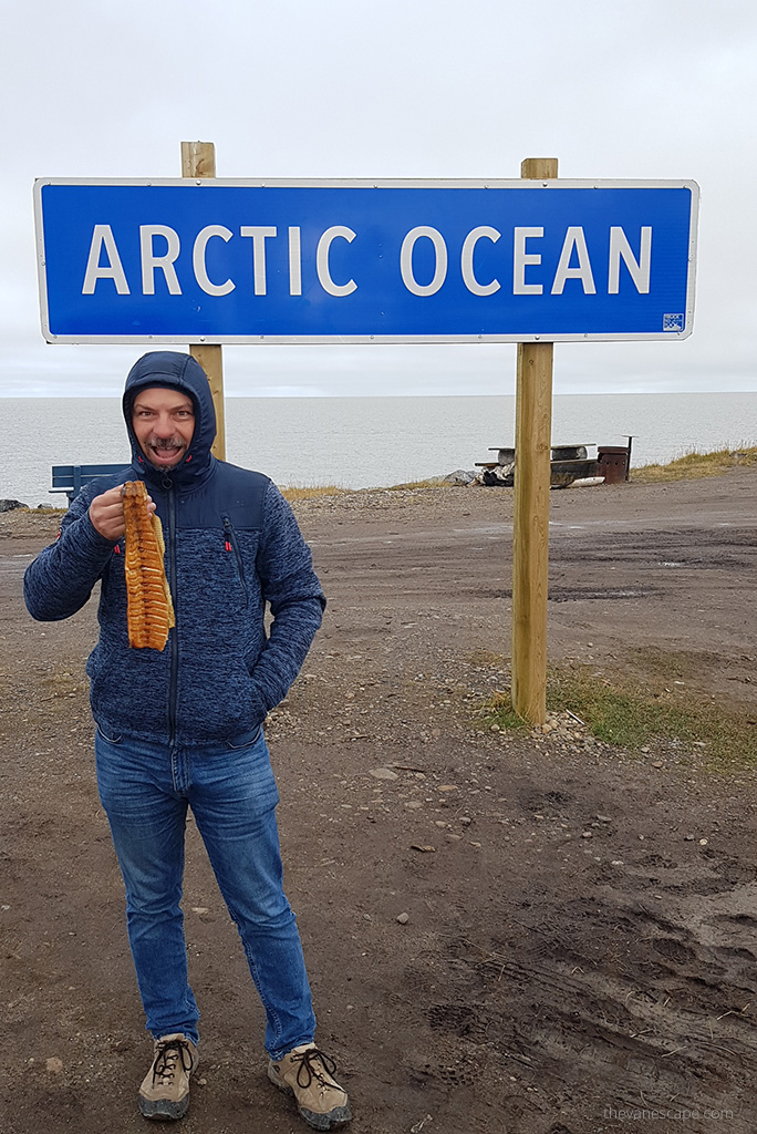 Chris eating dry fish at the Arctic Ocean in Tuktoyaktuk.