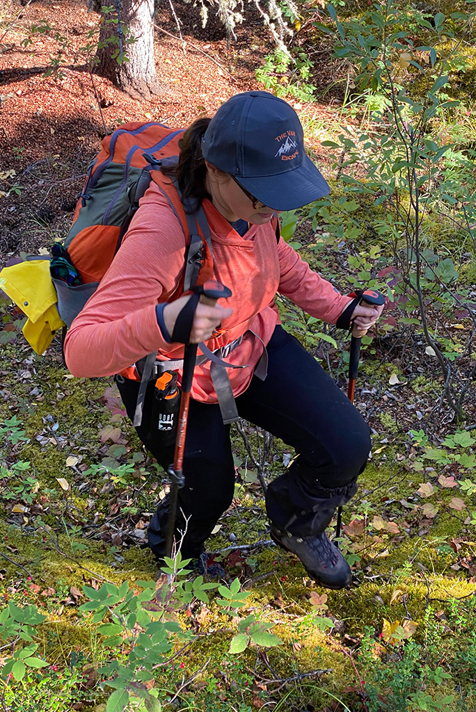 Agnes Stabinsa in orange KUHL ENGINEERED Women's Hoody is hiking in the forest.