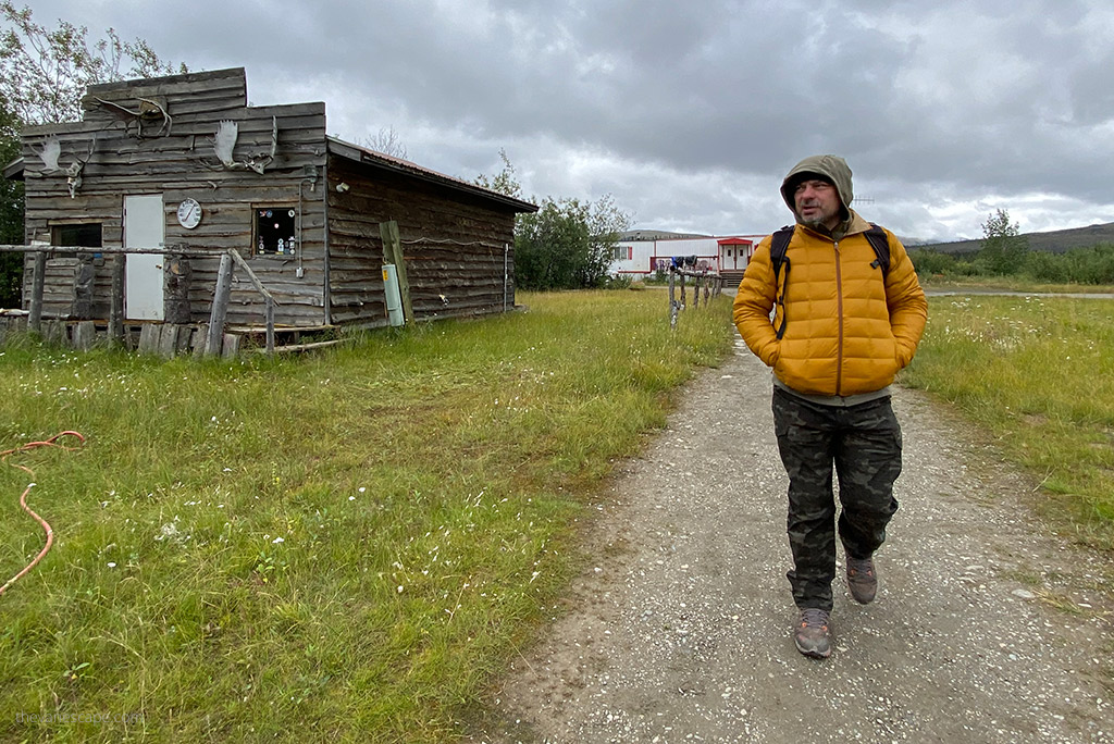 KUHL SILENCR ROGUE KARGO PANT REVIEW: Chris Labanowski, co-owner of the Van Escape blog, is hiking in pants by Kuhl next to a wooden buildling in Alaska.