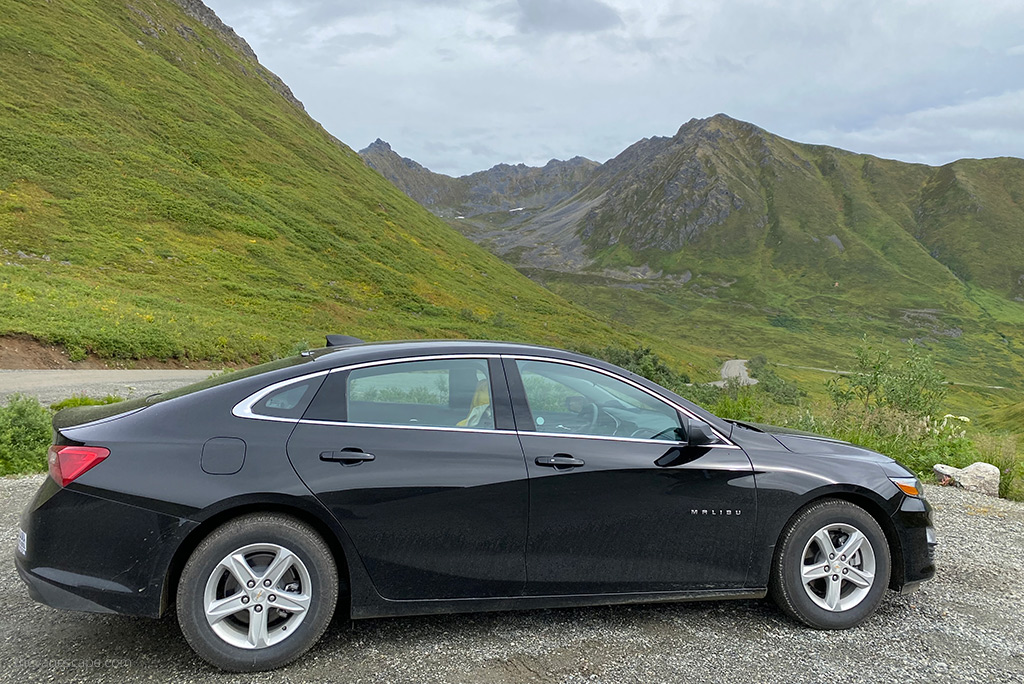 black rented malibu car among mountain scenery