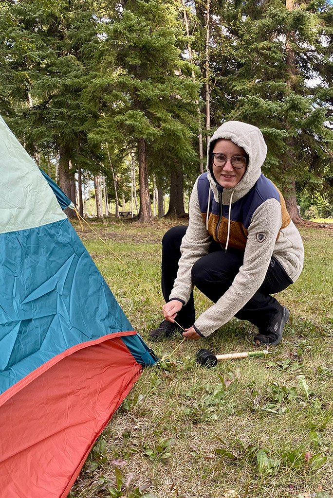 KUHL PRISM Hoody Review: Agnes Stabinska, the author, in a hoody is putting a tent.