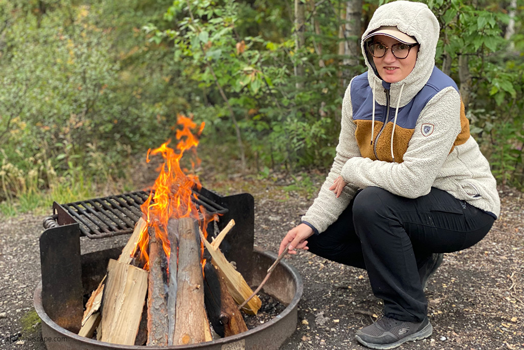 Agnes Stabinska in KUHL PRISM Hoody next to campfire in the forest.