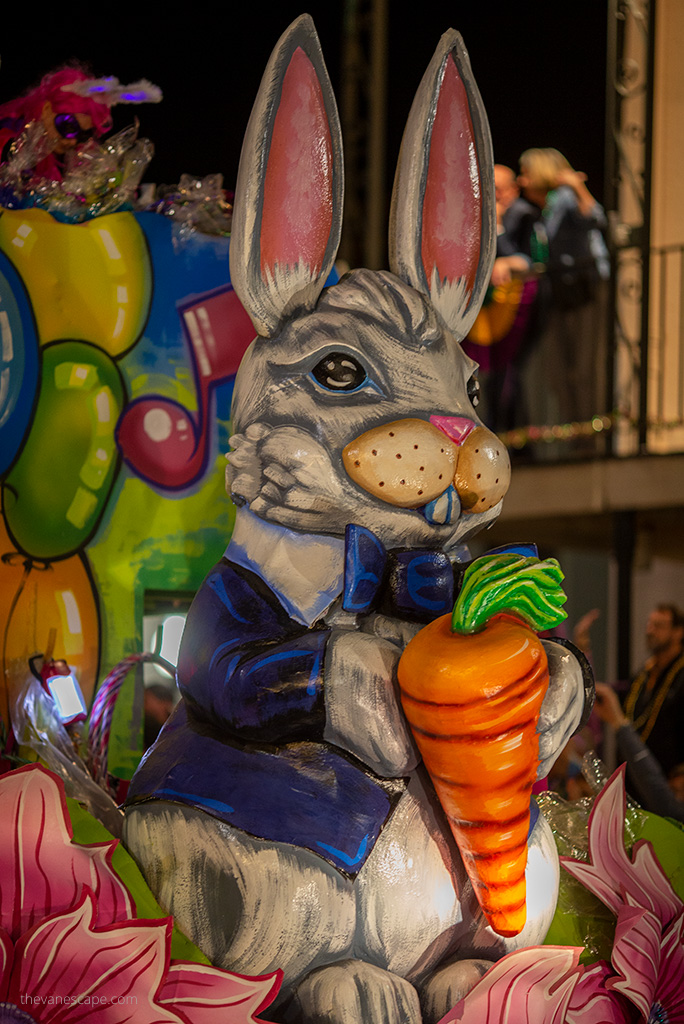 A colorful large hare holding a carrot on a platform wanders the streets of New Orleans