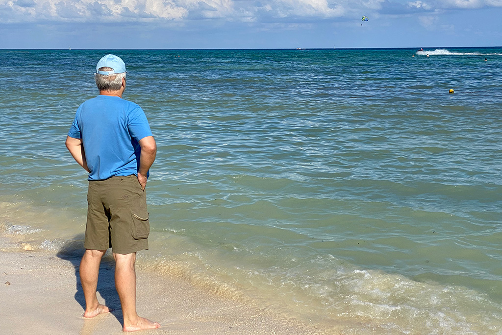 Chris Labanowski, co-founder of the Van Escape blog, is wearing KUHL AMBUSH Cargo Shorts. He is standing at the sandy beach ad admiring the blue sea.