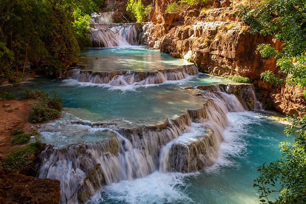 Cascading blue water of waterfalls on orange rocks. 