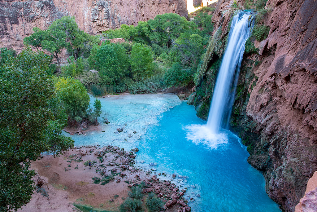 Stunning blue water of Havasu Falls flowing down high orange rocks.