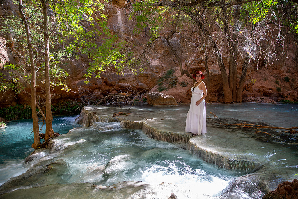 Agnes in white dress and hat standing in the water at havasu falls camping.