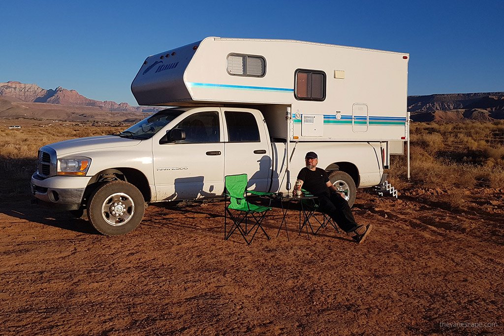 Chris Labanowski sitting during sunset next to our camper truck on the green camping chair and camping table.