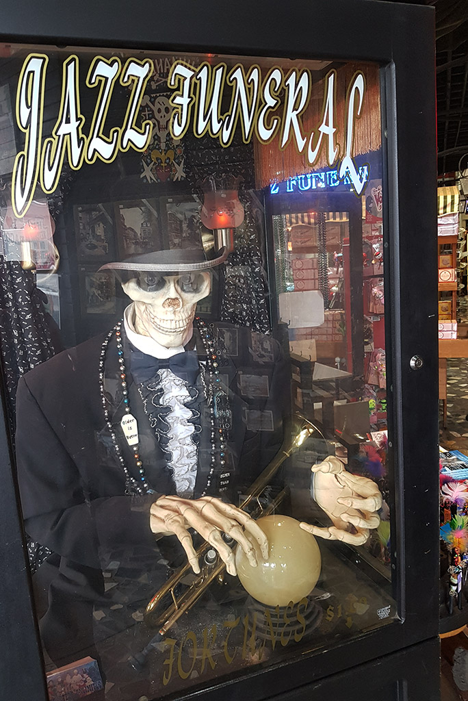 new orleans 3 days itinerary: souvenir shop window with a skeleton and the words jazz funeral.