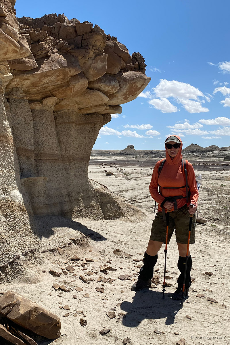 Agnes Stabinska, the author, hiking in Bisti Badlands. She has orange hoodie and trekking poles.