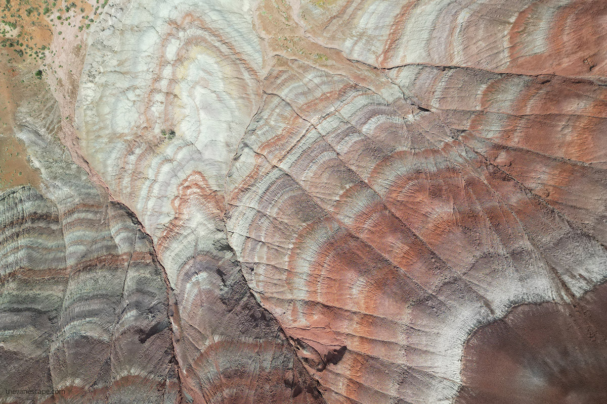 Aerial view (photo taken by drone) of Paria Rainbow Mountains rock layers, that have shades of rust, red, purple, purple, gray, and white