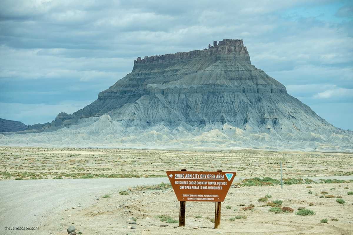 a wooden board informing about the area available for OHV vehicles; in the background  with huge Factory Butte