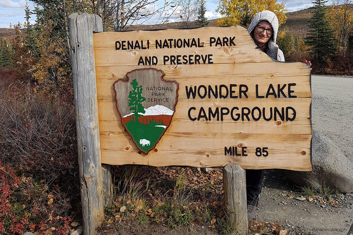 Agnes with sign of Wonder Lake Campground at mile 85 Denali Park Road
