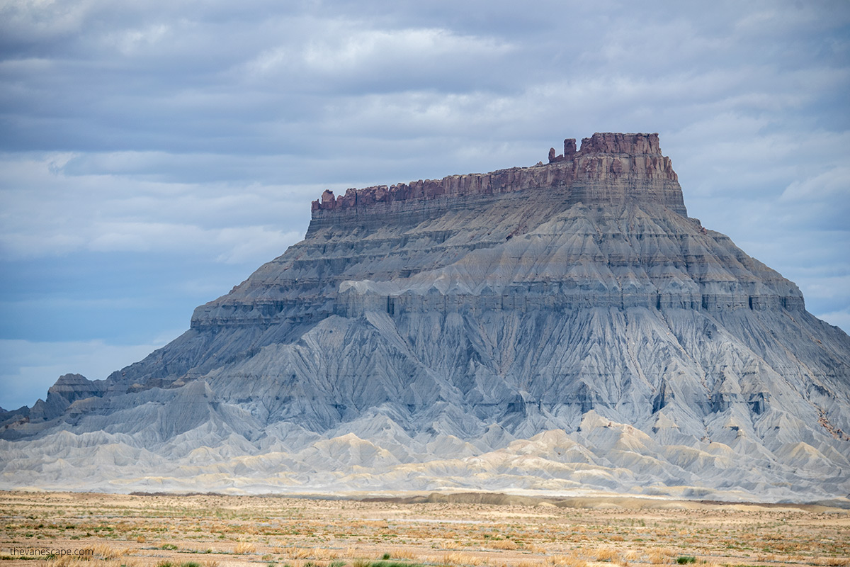 close-up of Factory Butte showing rock strata and rock surfaces with different colors of gray, and rusty