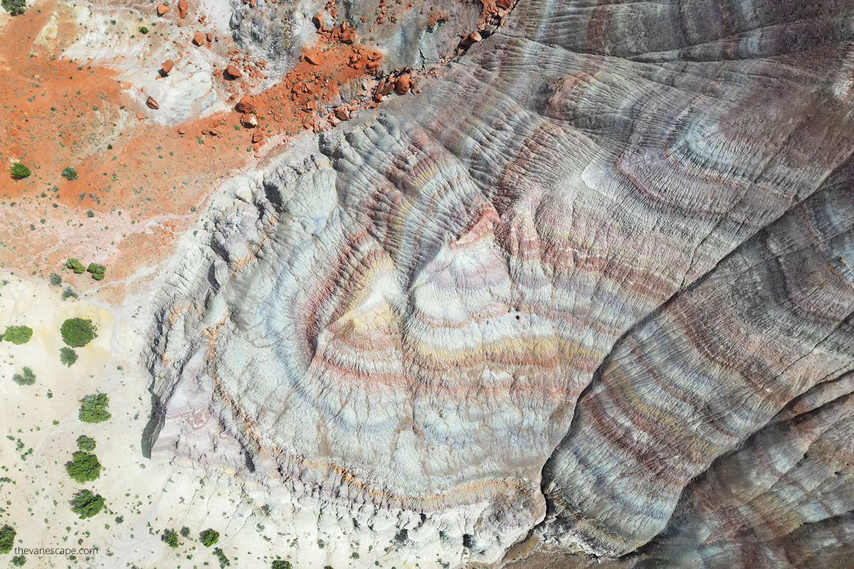 Aerial view (photo taken by drone) of Paria Rainbow Mountains rock layers, that have shades of rust, red, purple, purple, gray, and white
