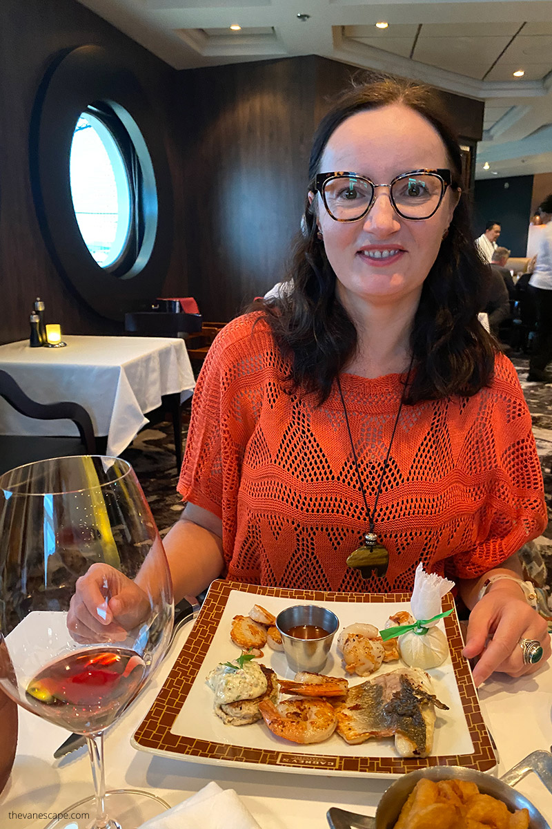 Agnes in orange blouse eating seafood in ship restaurant
