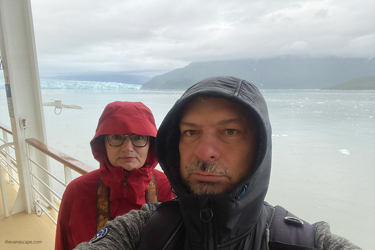 Agnes and Chris with windproof jacket on the cruise ship with the huge alaska glacier in backdrop