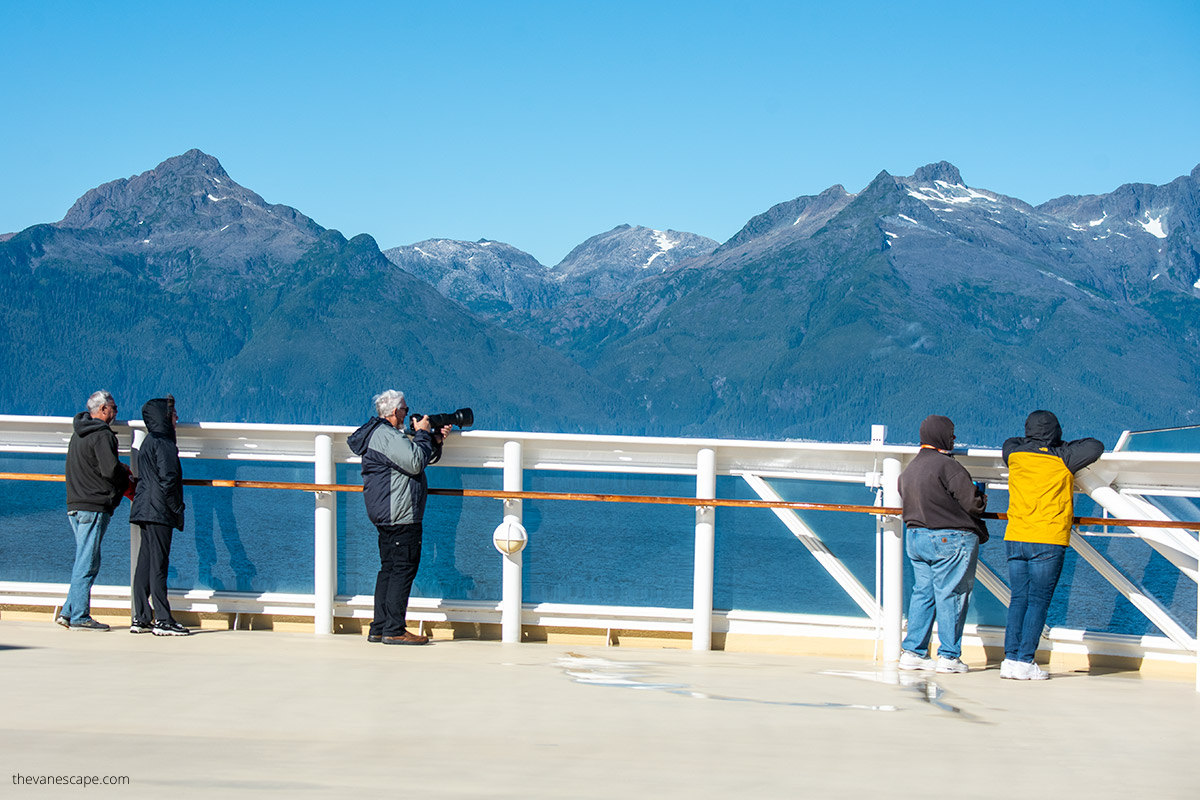 people on the ship dock admiring Alaska landscape wearing windproof jackets and taking pictures