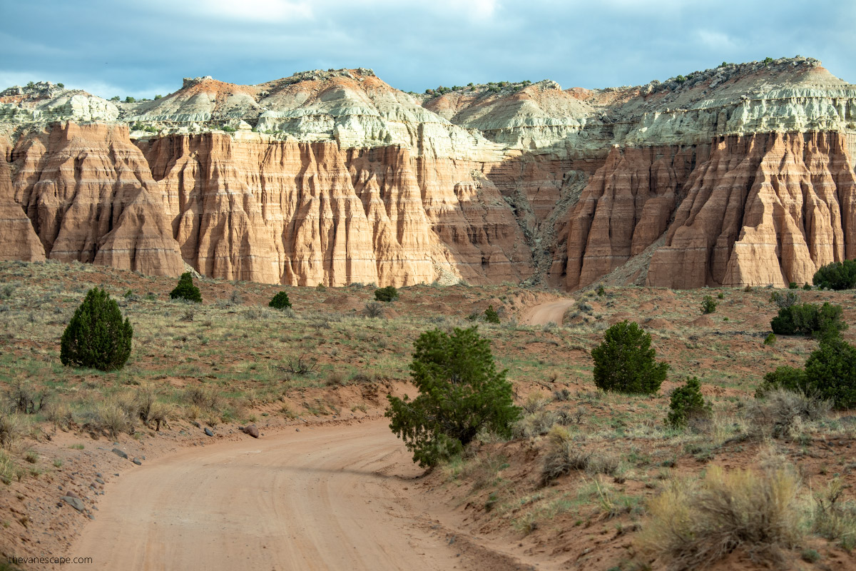 dirty sandy road and orange rock formations in cathedral valley