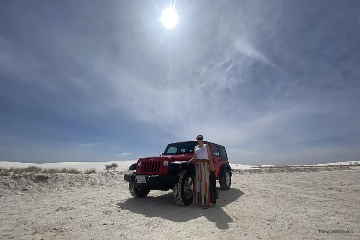 Agnes Stabinska is standing next to red jeep wrangler on the Dunes Drive in White Sands National Park.